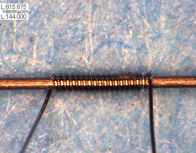 分析機器向けのレニウムコイル（芯線付きの状態） コイル径0.1mm、コイル長0.8mm程度の極小さいコイルです。